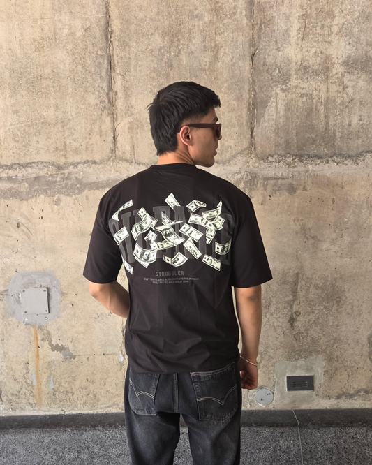 Person wearing a black t-shirt with white graphics against a stone wall.